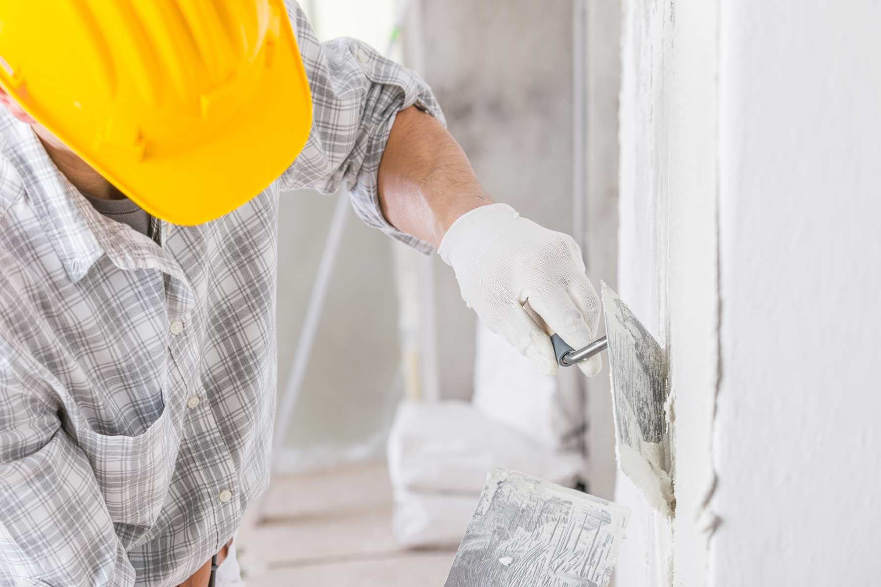 کارگر گچکار در حال اعمال گچ بر دیوار پس از تعمیرات، نمایش مراحل اولیه گچکاری